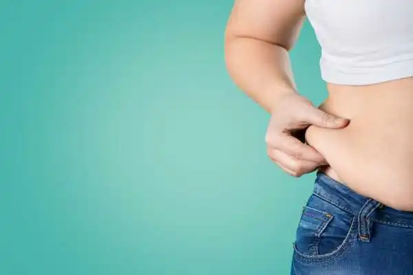 Image of woman pinching her love handles to show weight gain Clifton